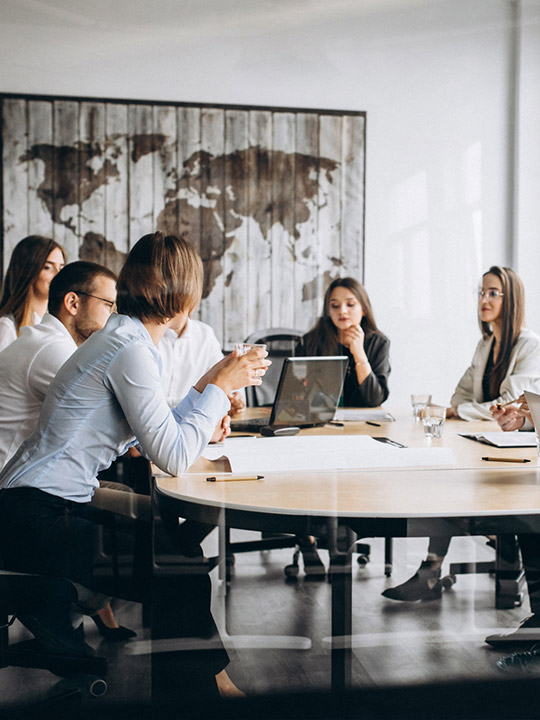Besprechung von Führungskräften in einem modernen Büro mit einer Weltkarte im Hintergrund