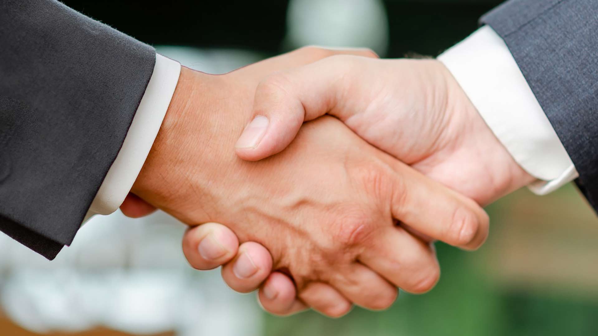 Geschäftspartner schließen eine Vereinbarung mit einem festen Händedruck, was Vertrauen und Zusammenarbeit symbolisiert